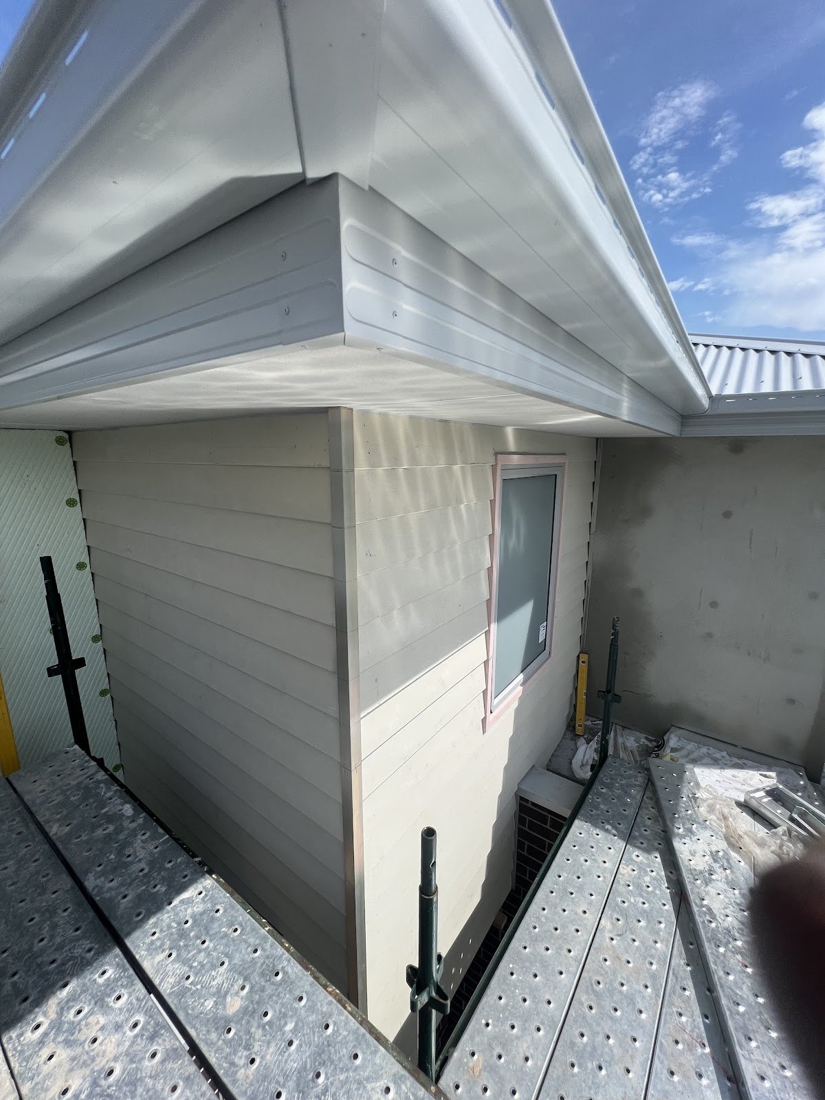 Upper storey corner with fresh cladding and new eaves under a blue sky