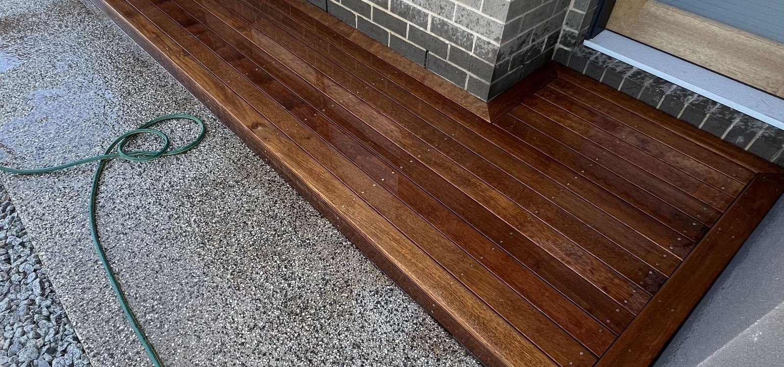 New merbau timber decking built against a dark brick home entrance